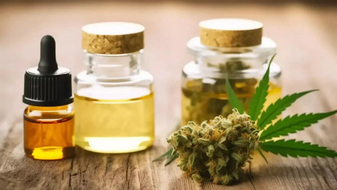 CBD oil bottles with a cannabis flower and leaf on a wooden surface
