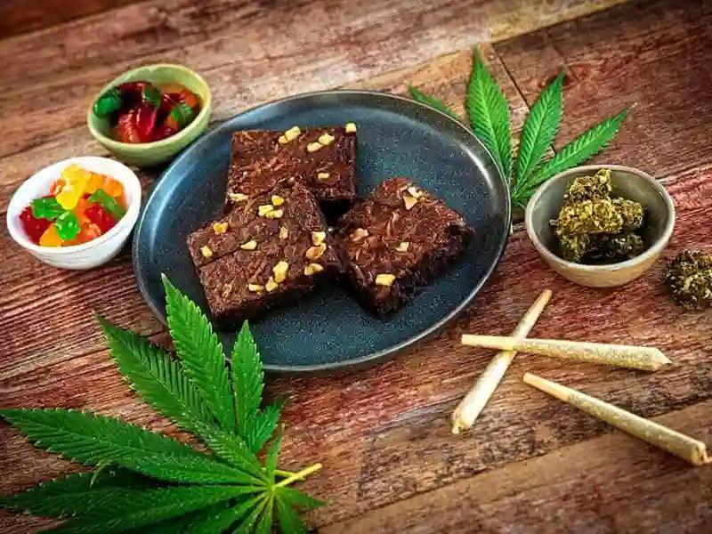 Assorted cannabis edibles, flower, and pre-rolls on a rustic wooden surface.