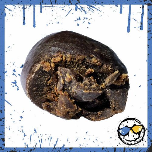 Close-up of a chocolate-coated cannabis edible with a bitten center revealing a textured interior.